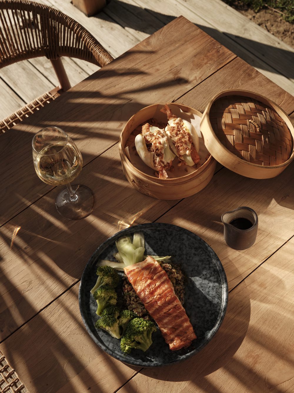 salmon dish with quinoa and broccoli, accompanied by dim sum and white wine