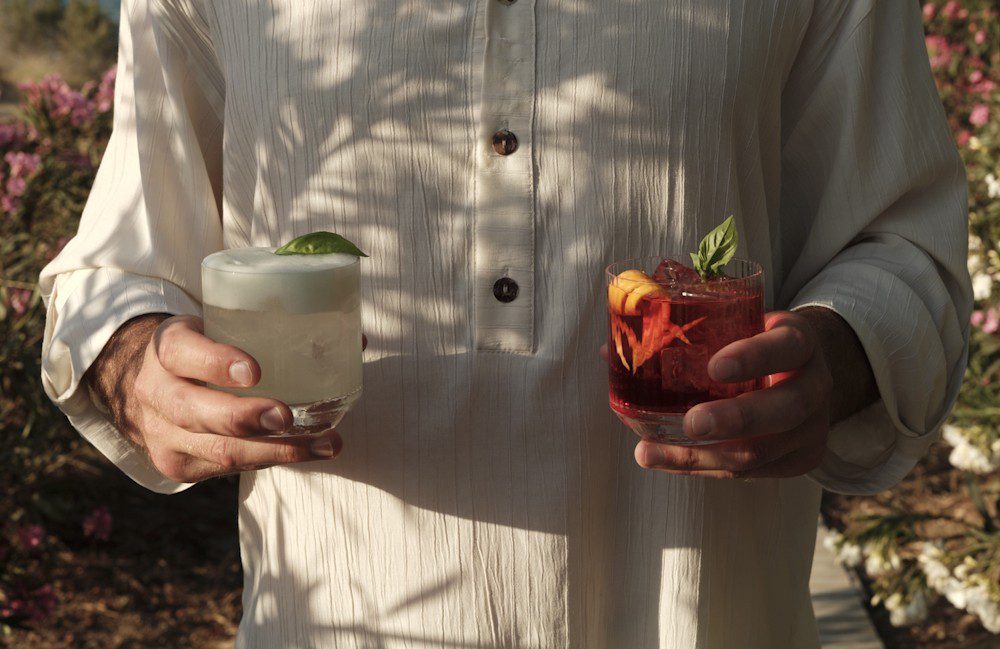 Hand holding cocktails at Banana Baya Beach Bar Restaurant